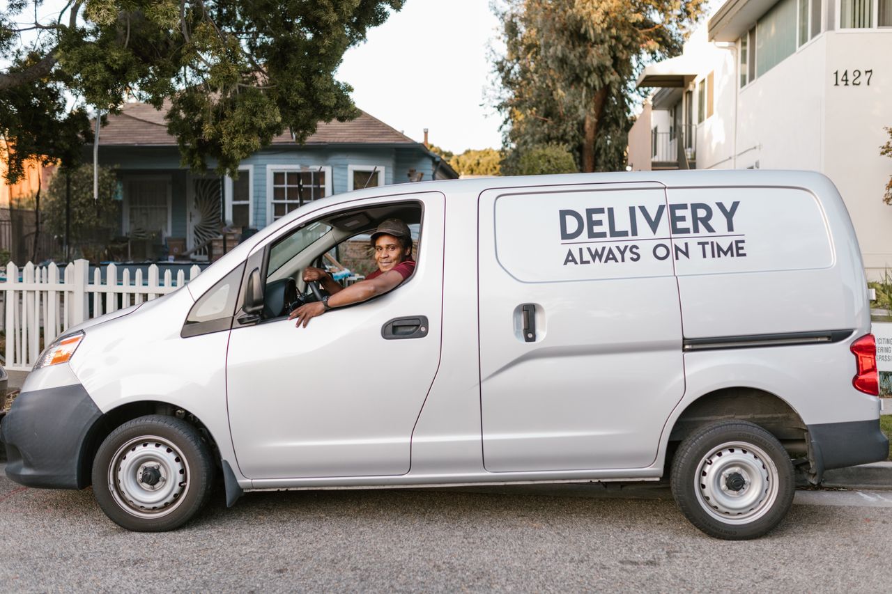 Courier driving a delivery van with 'Always On Time' service slogan parked in neighborhood.